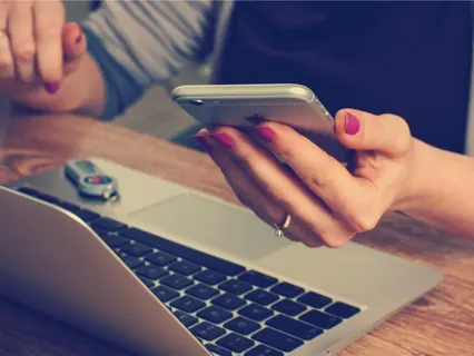 Mãos com celular e notebook no escritório