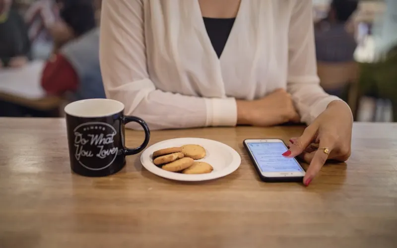 Mulher com celular e café