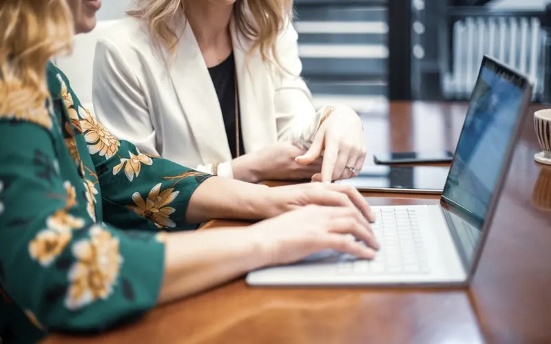 Mulher com celular e notebook no escritório